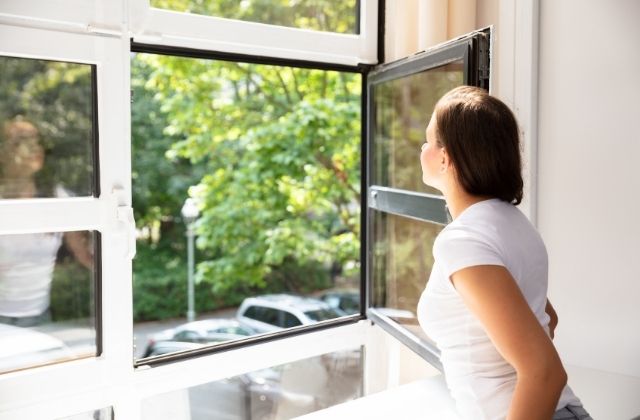 Kobieta wyglądająca przez okno zamontowane przez firmę Okno-Świat